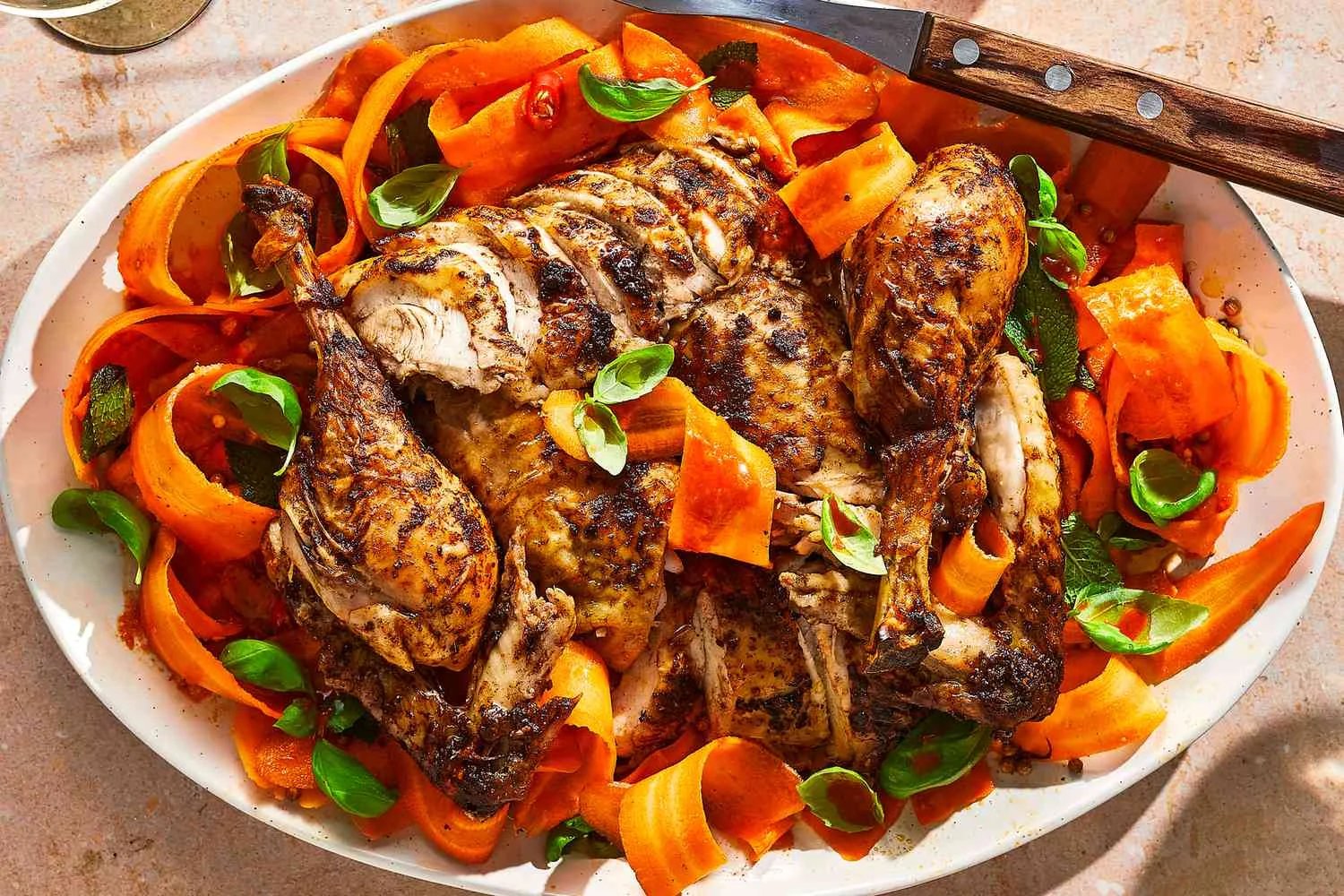 A platter of carved divorce chicken, served on top of a carrot ribbon salad