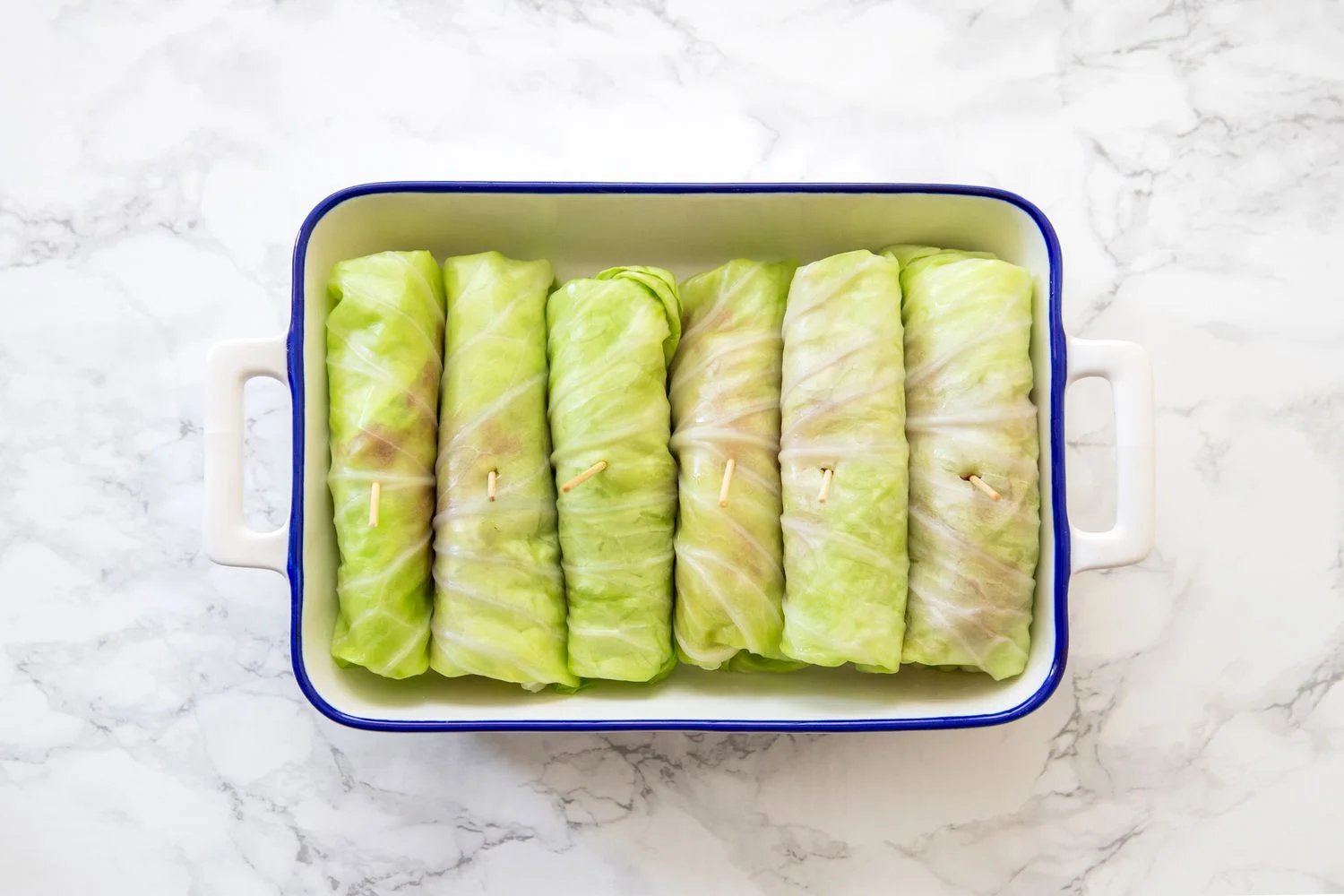 Cabbage rolls with a toothpick in a casserole pan