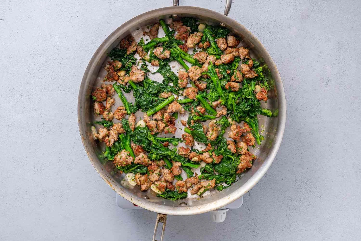 Broccoli rabe added to the pan with sausage