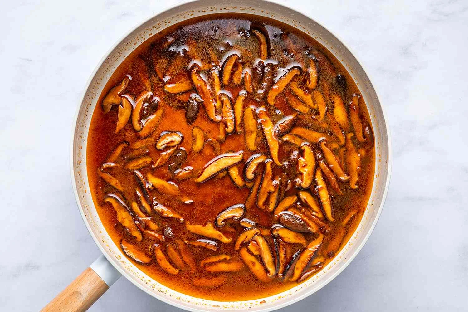 A skillet with the reserved pasta water, cooked shiitake mushrooms and shallots