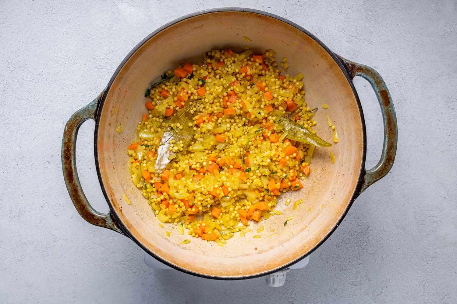 Thyme leaves and stalks and pasta added to the vegetable mixture