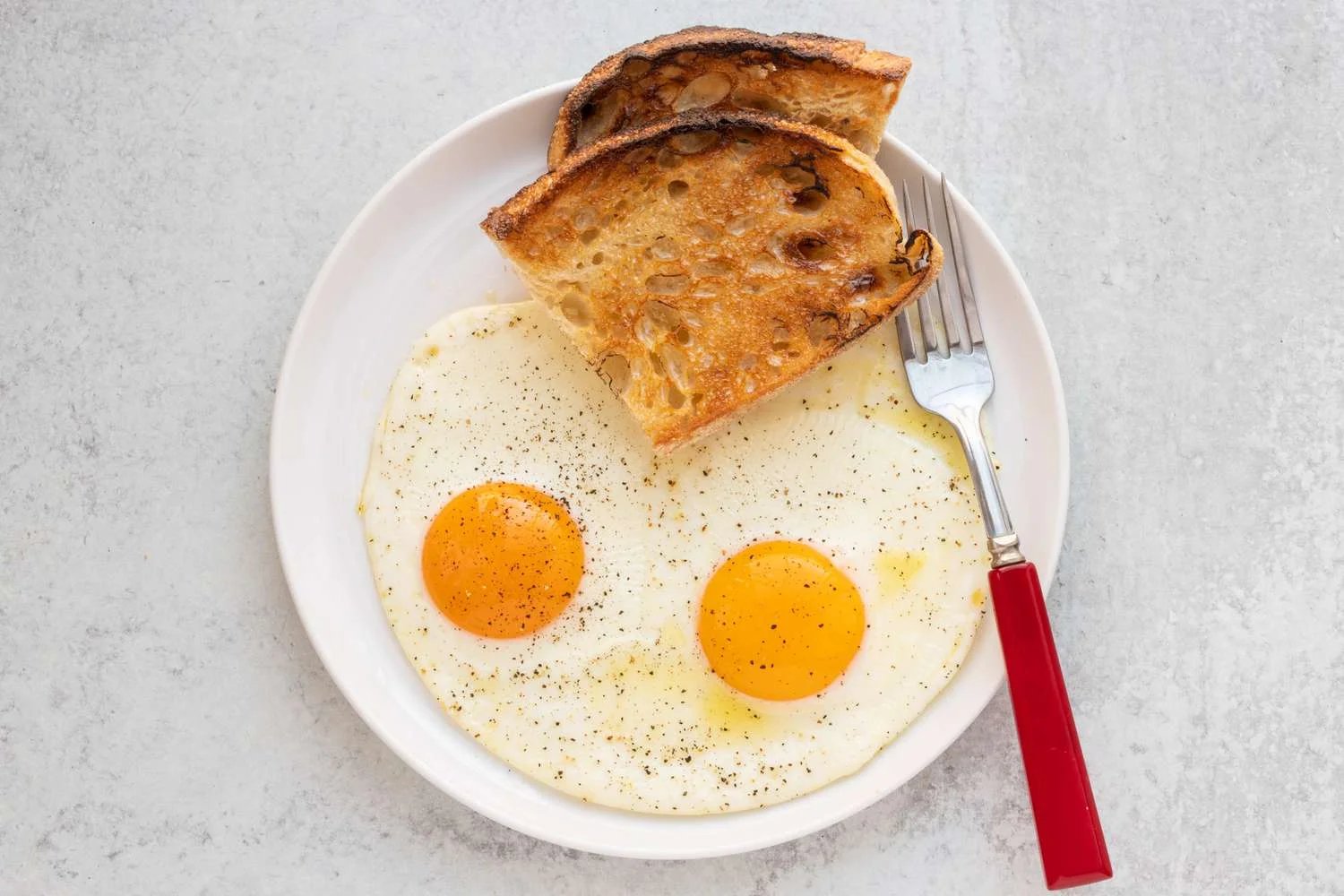 Two sunny-side up eggs on a plate with toast.