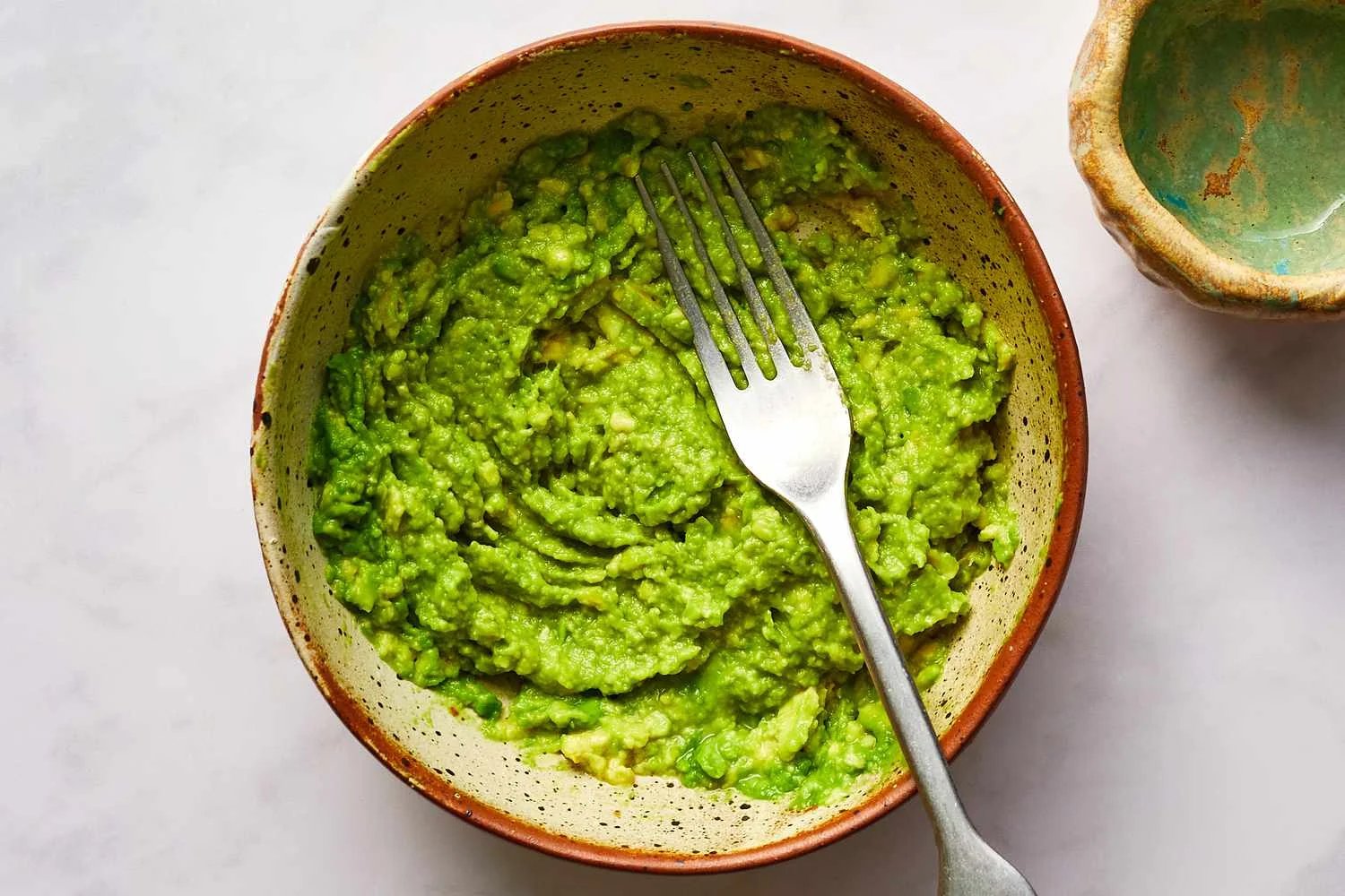 Mashed avocado in bowl with fork