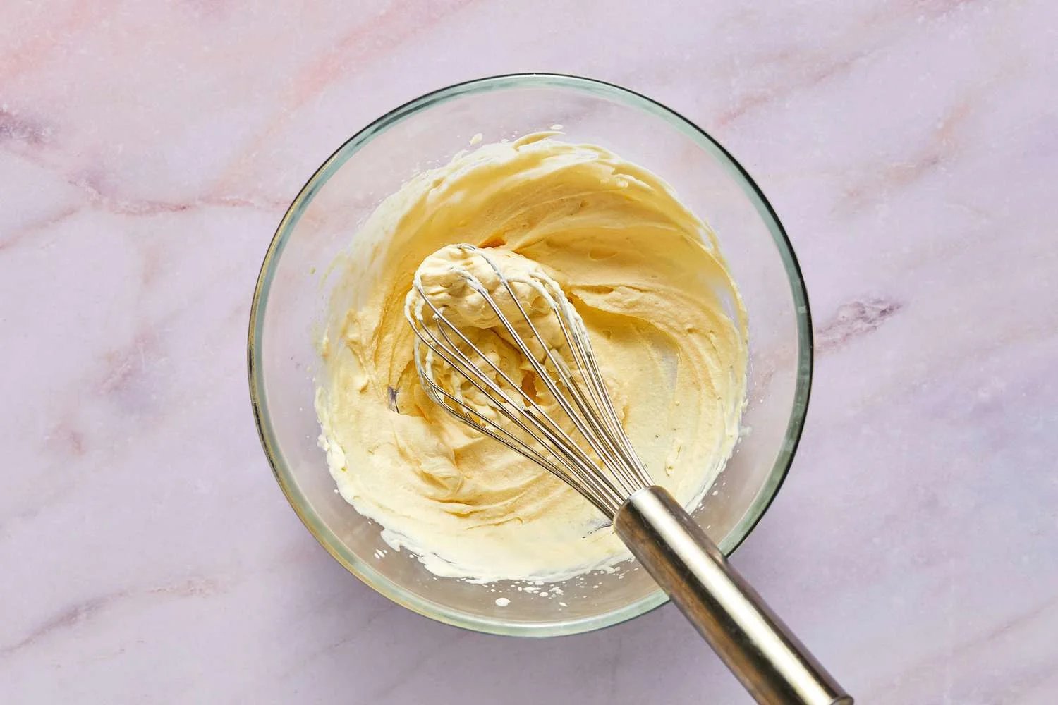 A bowl of whipped cream with a whisk