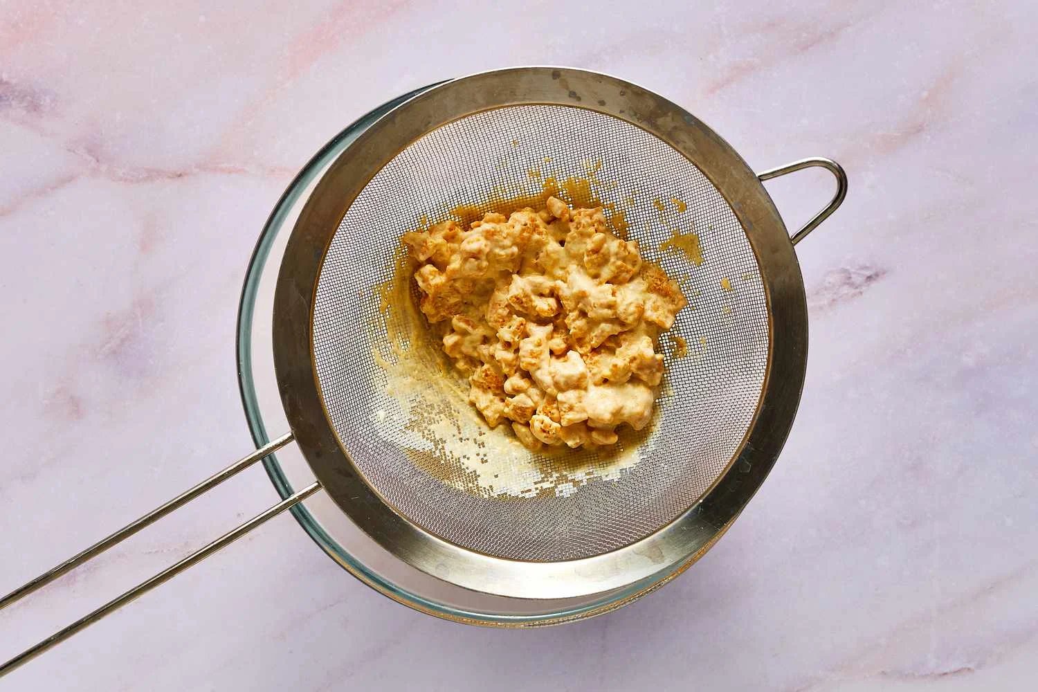 A strainer with soaked Cap'n Crunch cereal