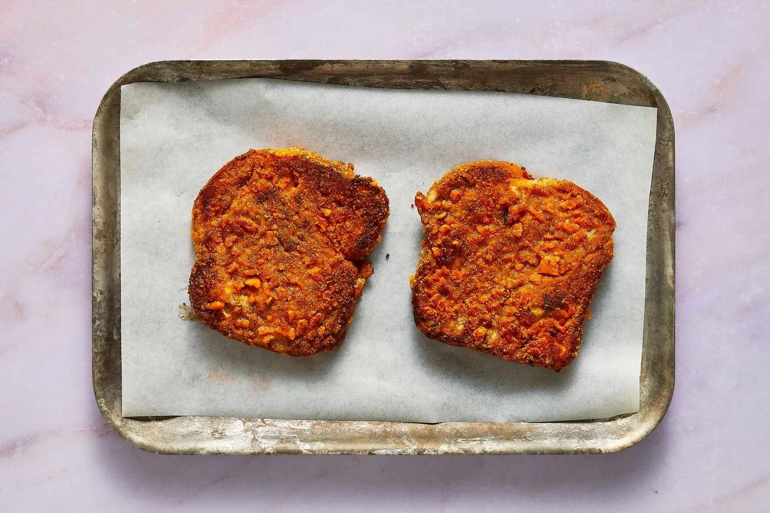 A parchment paper lined baking sheet with two pieces of French toast