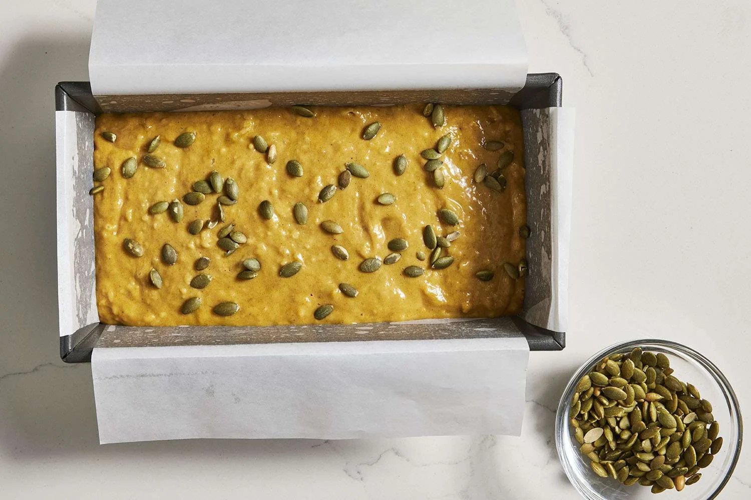 pumpkin seeds on top of banana pumpkin bread batter