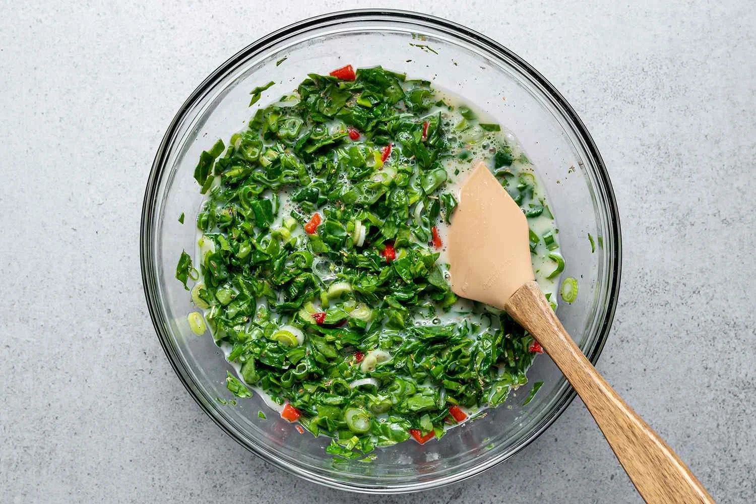 Adding chopped spinach, roasted red peppers, green onions, salt, pepper, and Italian seasoning to the egg white and sour cream mixture