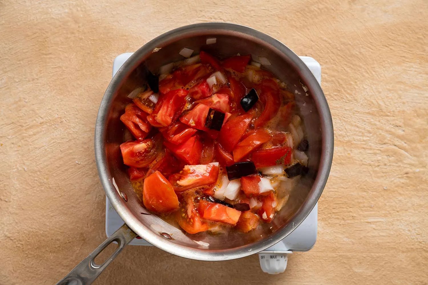 Guajillo chiles, tomatoes, onion, garlic, and water in a saucepan on a burner 