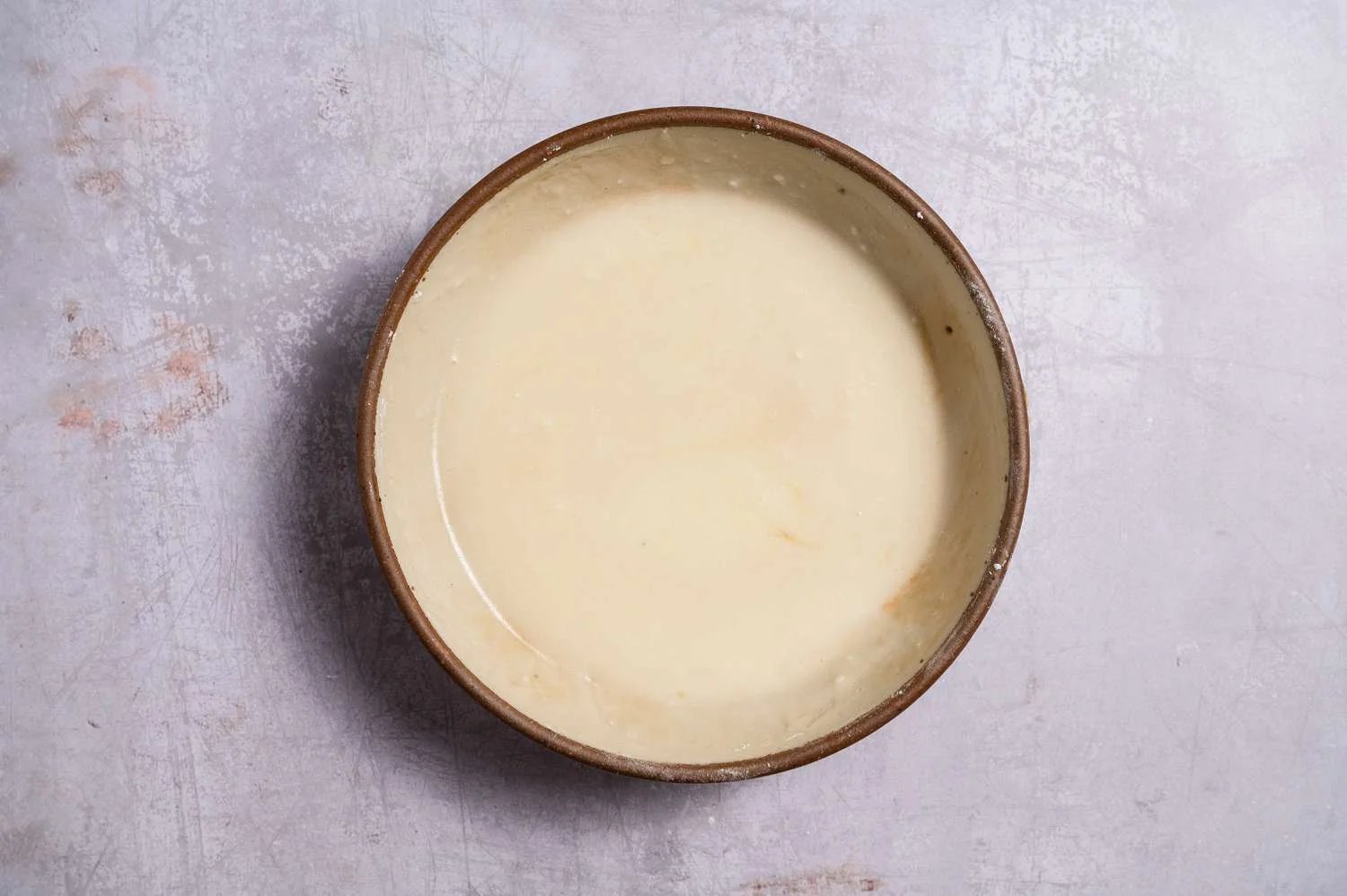 A bowl of combined confectioners' sugar, melted butter, milk, and vanilla extract