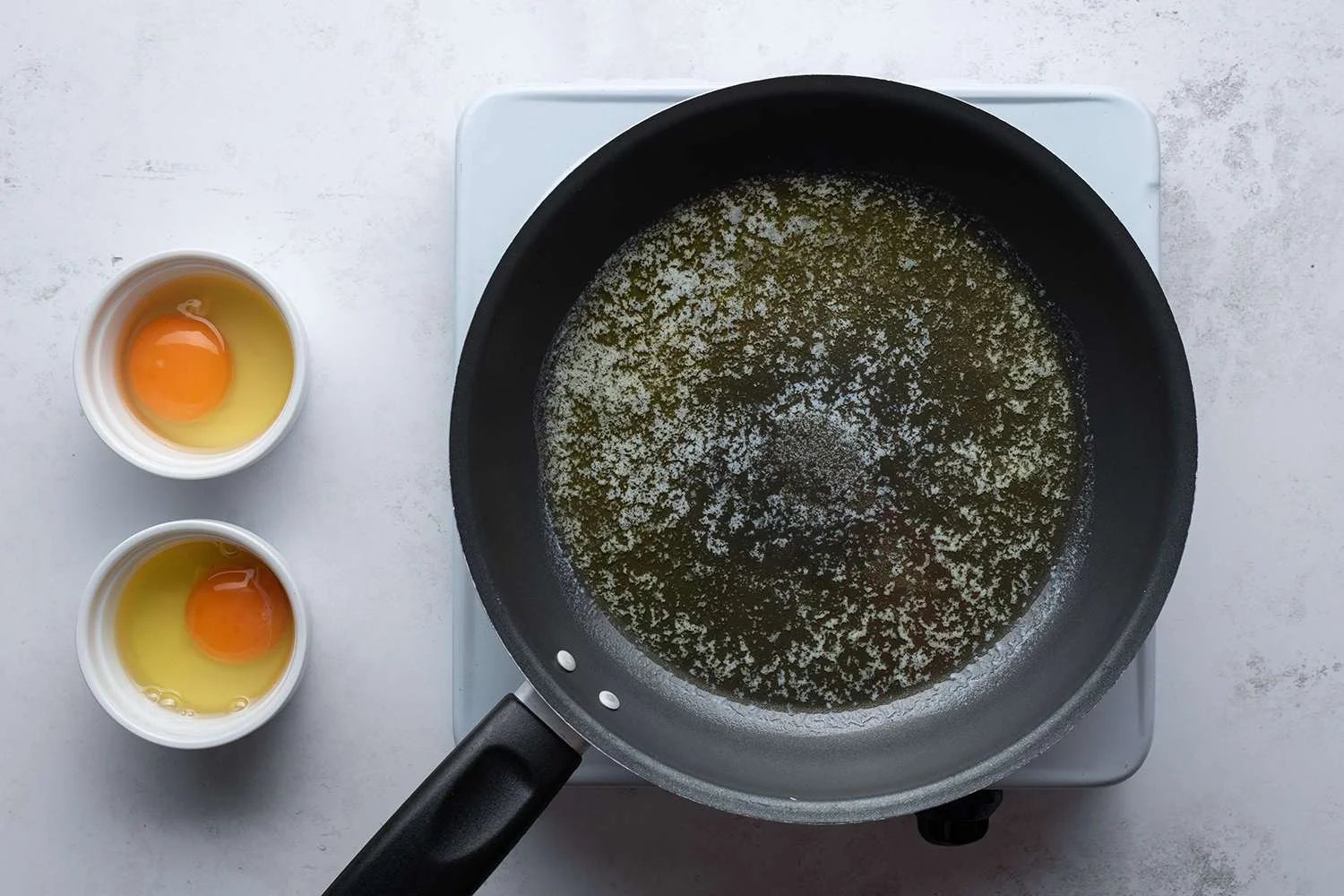 Eggs in ramekins next to a skillet